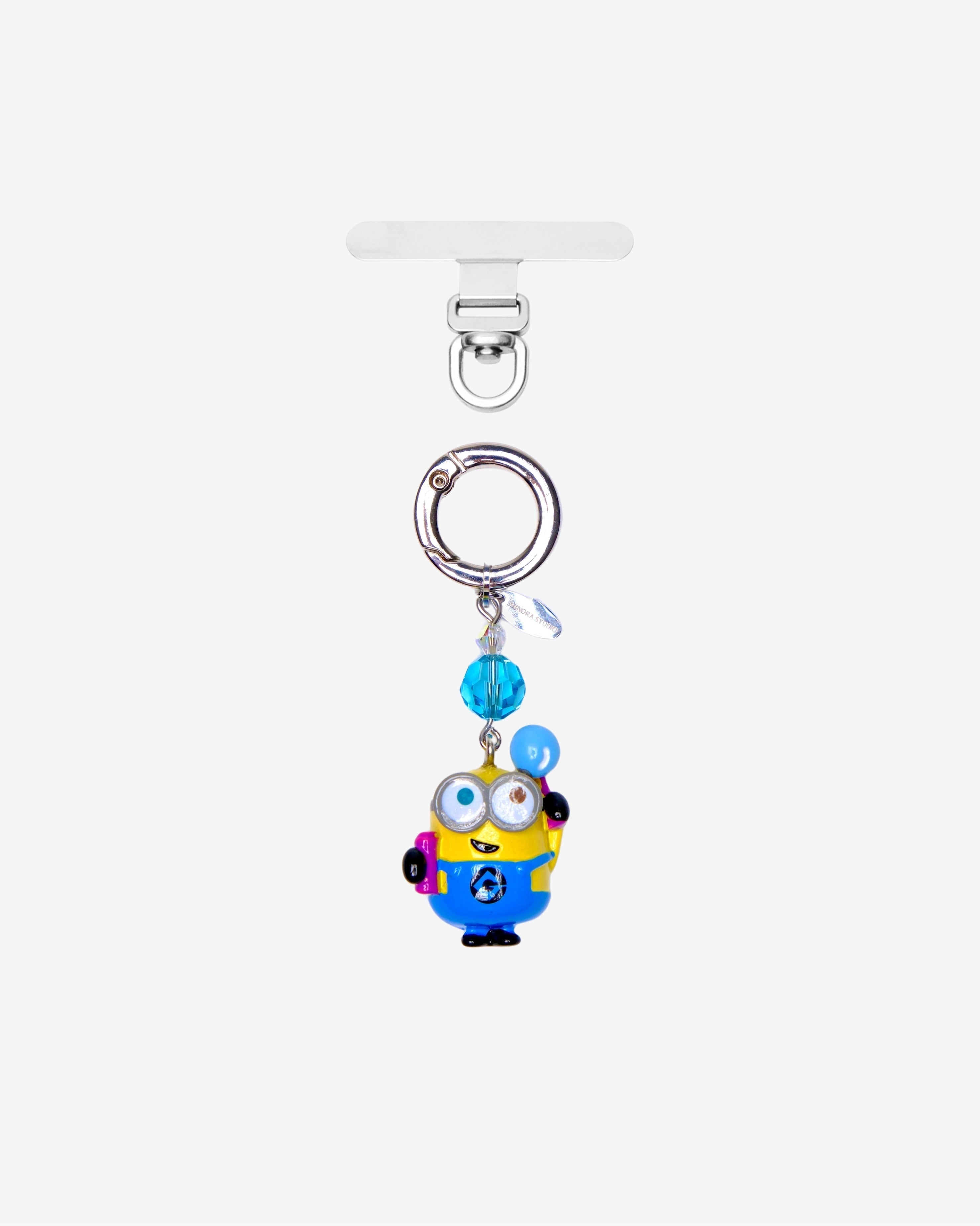 Yellow goggle-eyed character phone charm holding a blue balloon