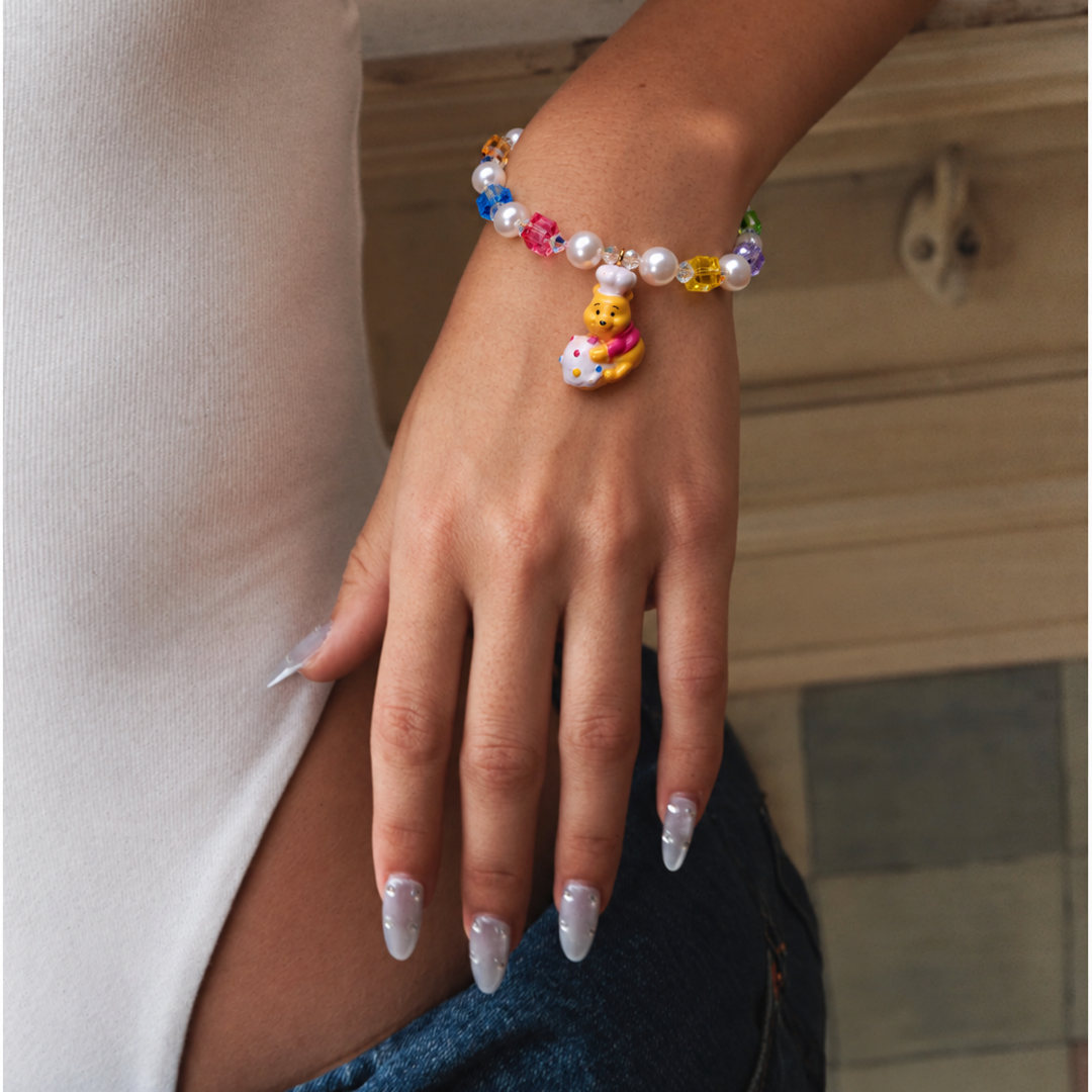 Honey Baker Charm Bracelet with rainbow crystal cubes, white pearls and a bear chef charm, worn with a white top and jeans.
