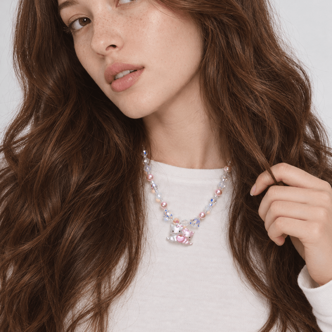 Sweethearts Cat Duo Necklace with pink pearls, iridescent crystals and a cat-pair heart pendant, worn with a white top.