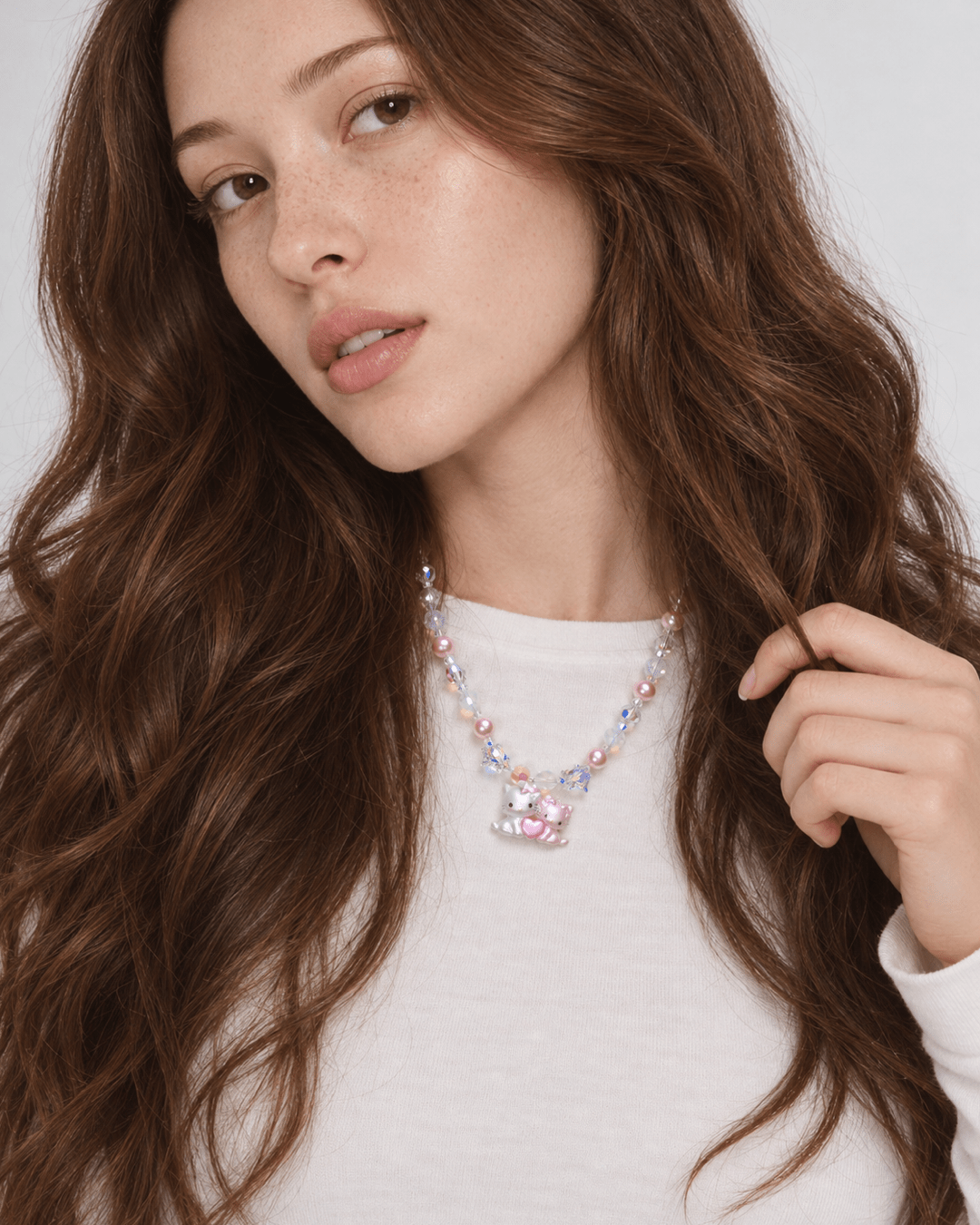 Sweethearts Cat Duo Necklace with pink pearls, iridescent crystals and a cat-pair heart pendant, worn with a white top.