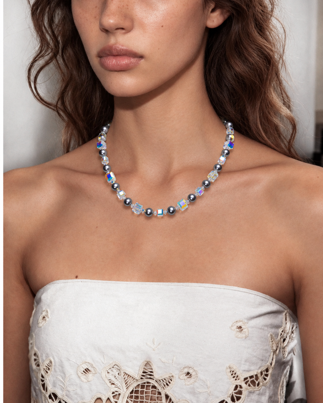 Midnight Prism Pearl Choker with dark gray pearls and iridescent crystal cubes, worn with a white embroidered strapless top.