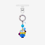 Yellow goggle-eyed character phone charm with a blue crystal accent, silver ring and clear attachment tab.