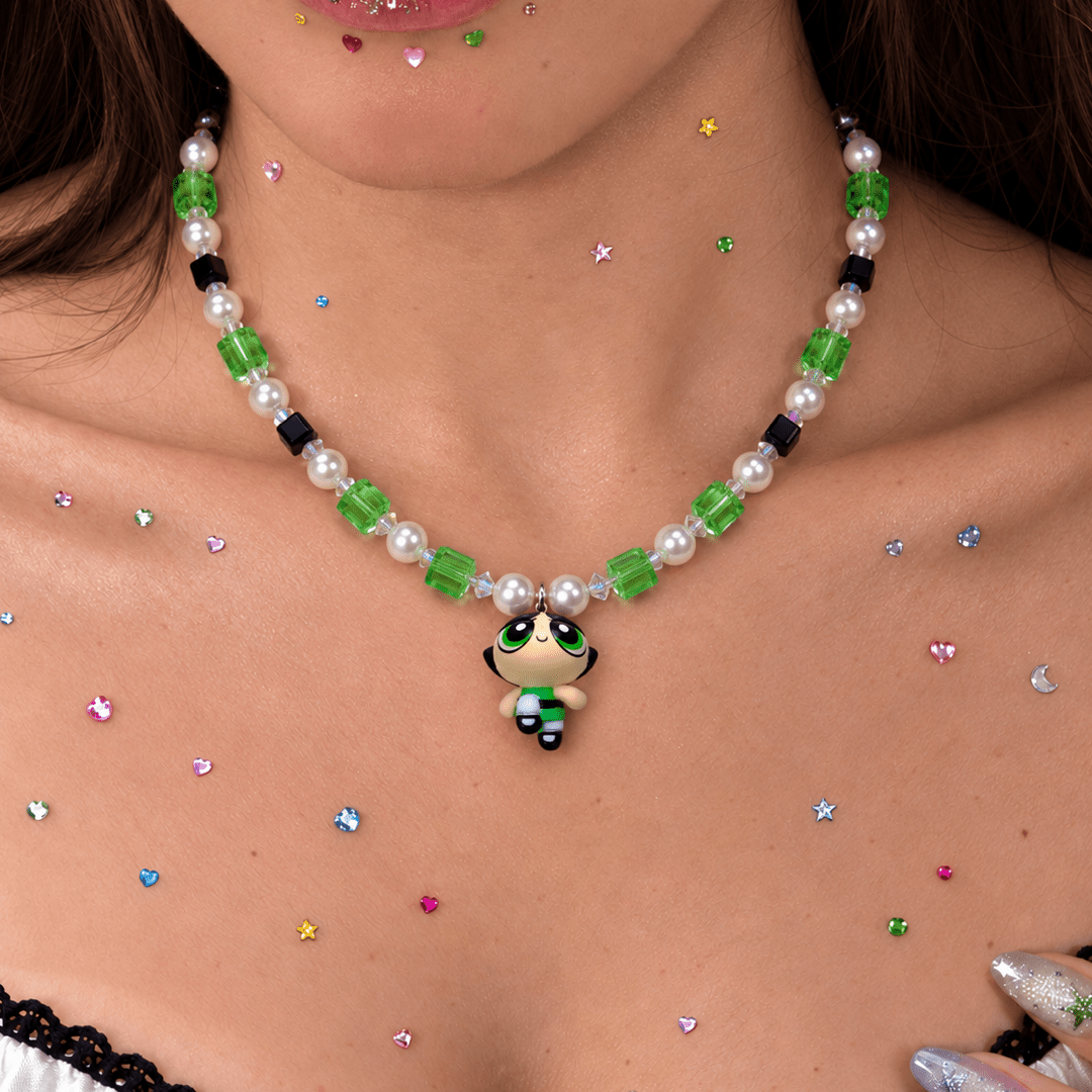 Green Force Charm Necklace with green and black crystals, white pearls and a girl pendant, worn above a lace-trimmed top.
