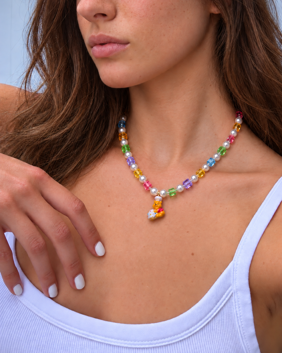 Honey Baker Charm Necklace with rainbow crystal cubes, white pearls and a bear chef pendant, worn with a pale tank top.