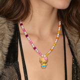 Tropical Sunshine Charm Necklace with pink and golden crystals, white pearls and a flower-wearing cat pendant, worn with a black top.