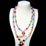 Rainbow crystal and pearl vampire mouse necklace layered below a pink witch mouse necklace on a white bust.
