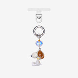 White dog phone charm with a brown ear, an iridescent crystal heart and silver-tone attachment hardware, shown on white.