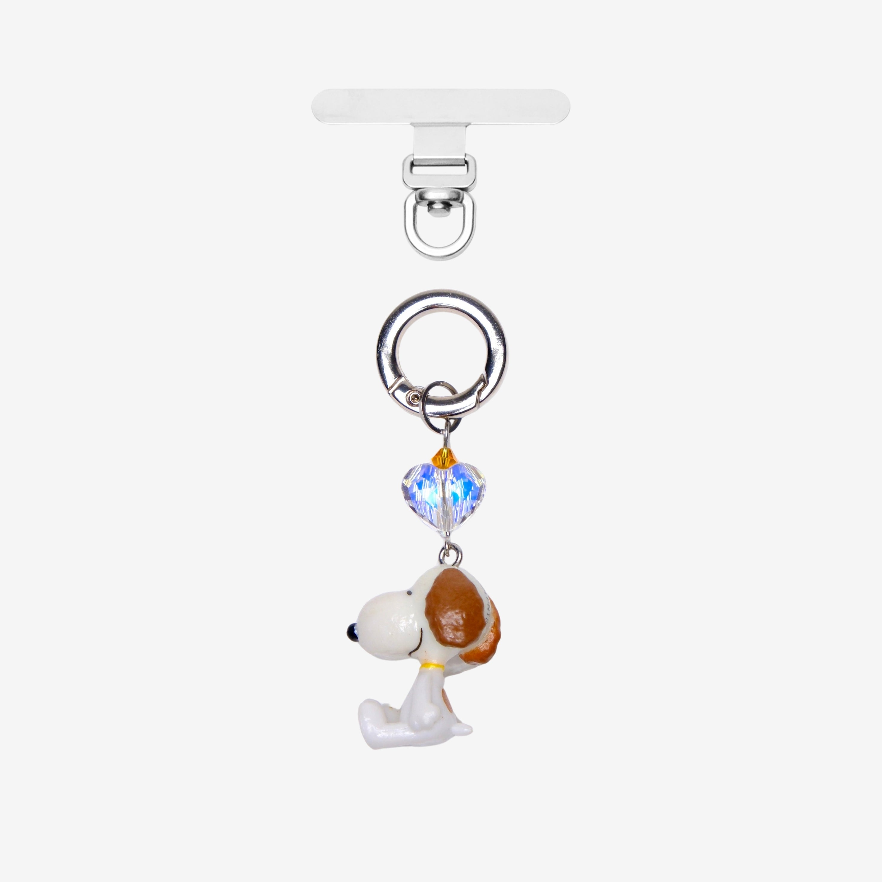White dog phone charm with a brown ear, an iridescent crystal heart and silver-tone attachment hardware, shown on white.