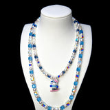 Blue and clear crystal double-layer necklace with white pearls and a snowboard cat charm, displayed on a white bust.