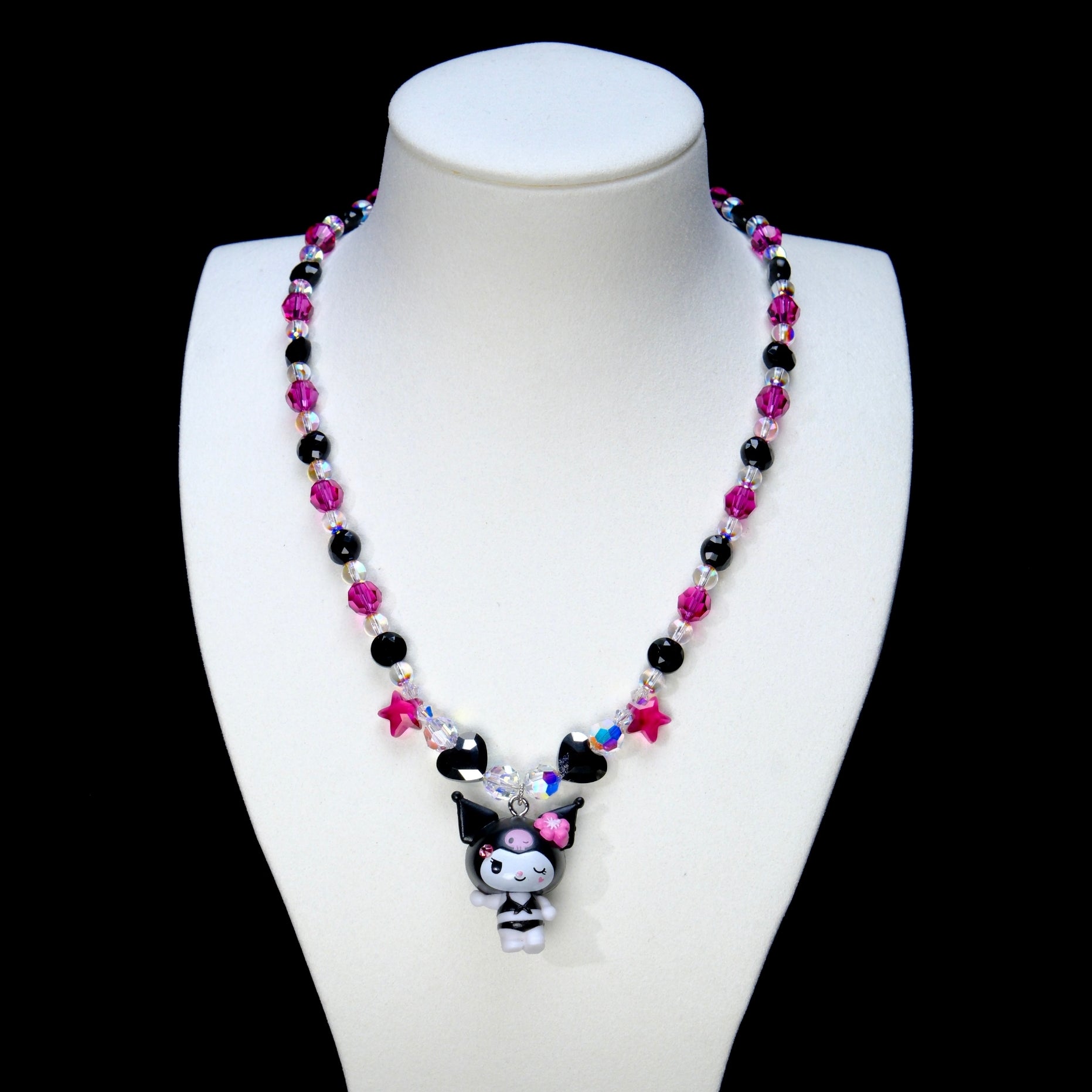 Pink and black crystal necklace with star and heart beads and a winking character charm on a white display bust.