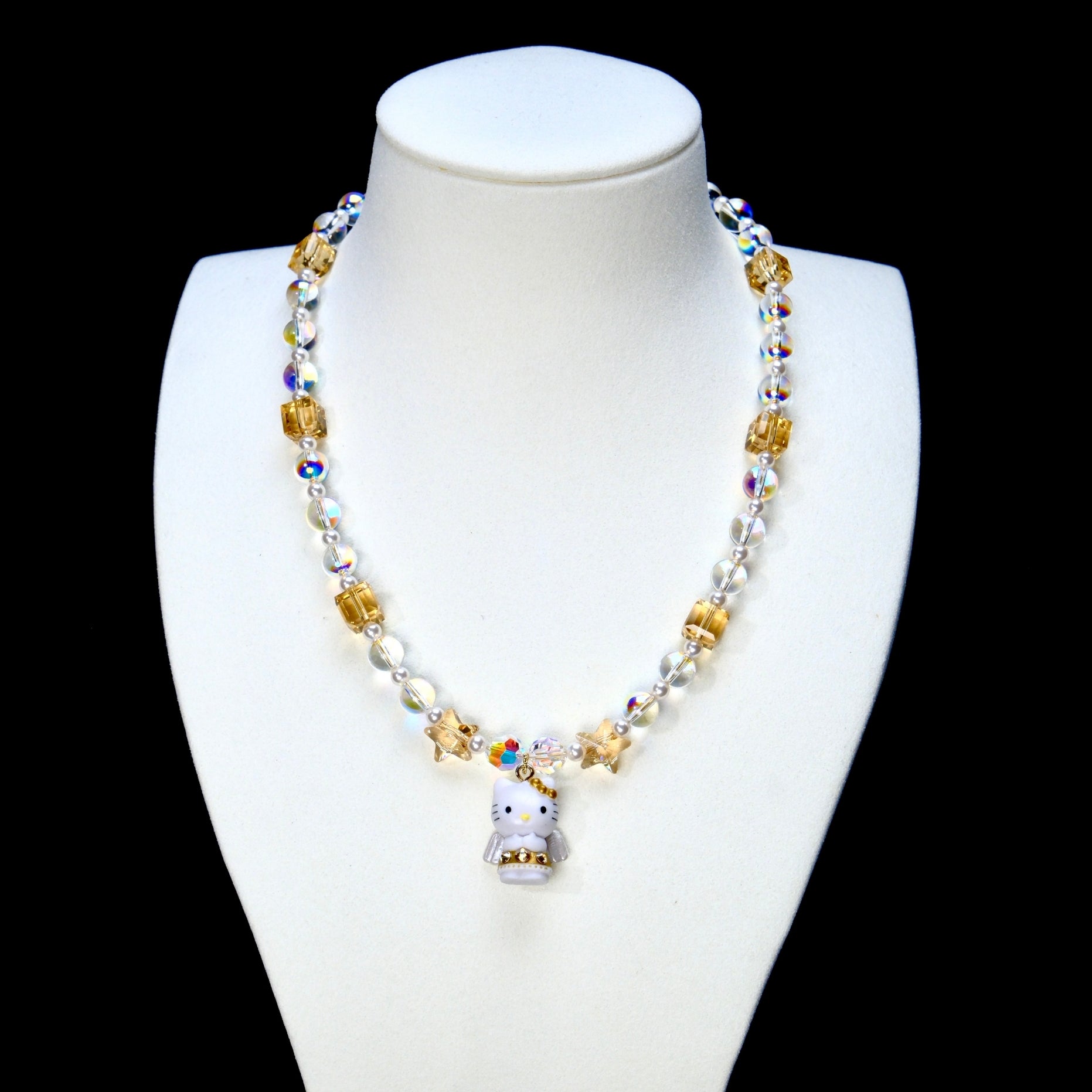 Champagne and iridescent crystal necklace with pearl accents and a winged cat charm on a white display bust.