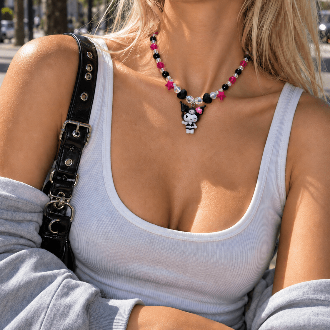 Woman in a gray tank top wearing a pink and black crystal necklace with star beads and a winking character charm.