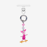 Detachable phone charm with a pink animal figure on a yellow skateboard, pink crystal accents and a silver-tone ring.