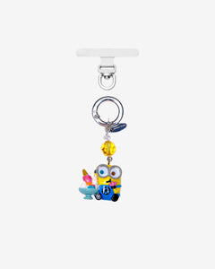 Yellow goggle-eyed character phone charm holding a sundae, with a yellow crystal accent and silver attachment ring.