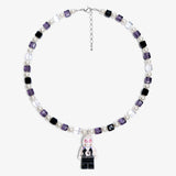 Studio product photo of a handmade pastel crystal charm necklace with white pearl accents and a playful vintage-inspired pendant.