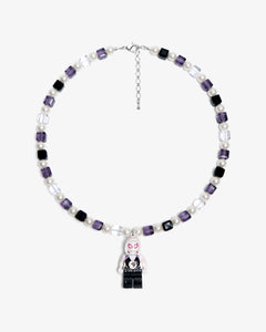 Studio product photo of a handmade pastel crystal charm necklace with white pearl accents and a playful vintage-inspired pendant.