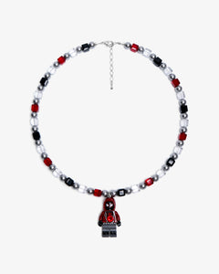 Studio product photo of a handmade red, black, and clear crystal charm necklace with pearl accents and a city-inspired collectible pendant.