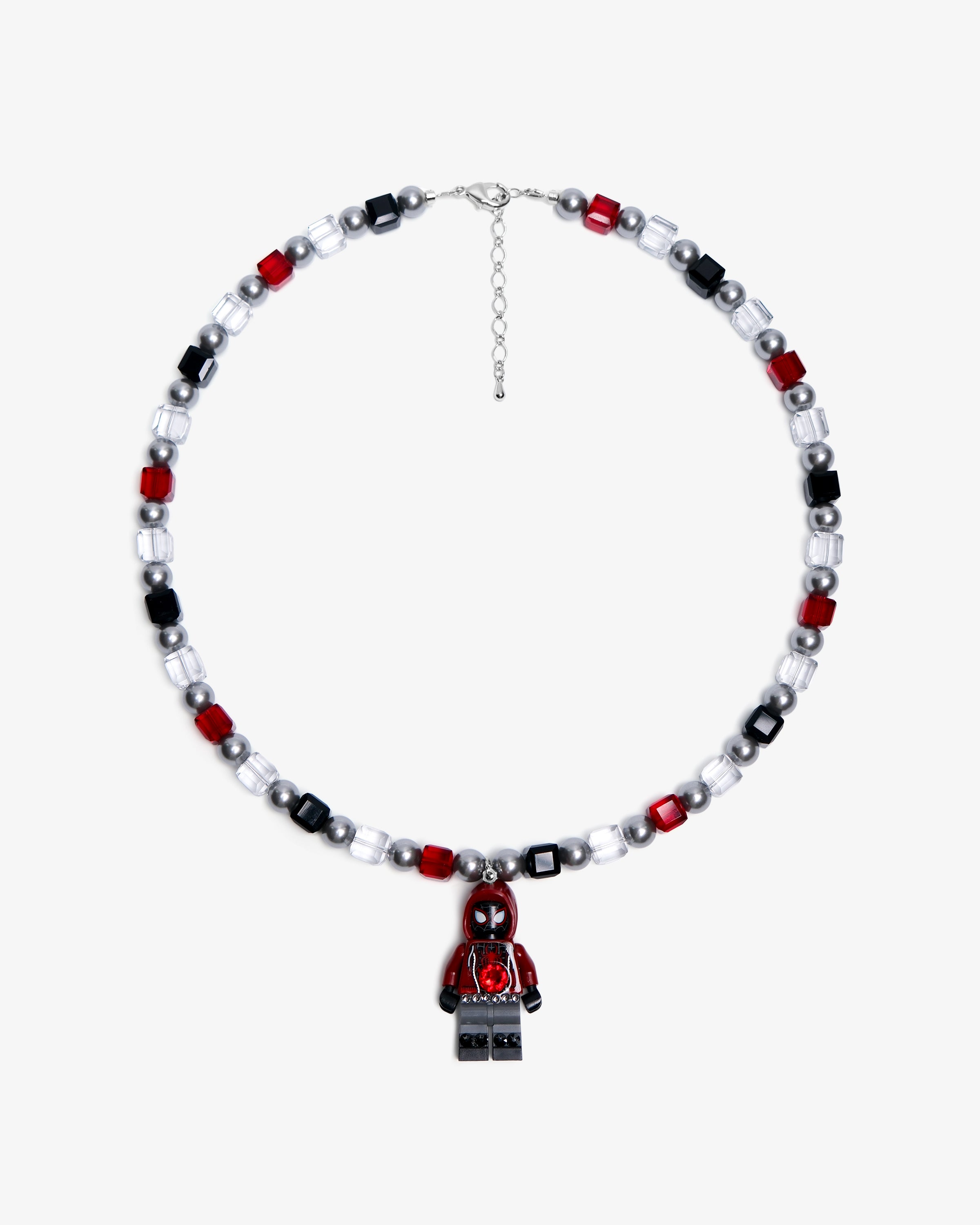 Studio product photo of a handmade red, black, and clear crystal charm necklace with pearl accents and a city-inspired collectible pendant.