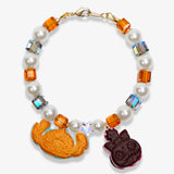 Studio product photo of a handmade cookie Swarovski crystal charm bracelet with pearls and vintage-inspired charm details.