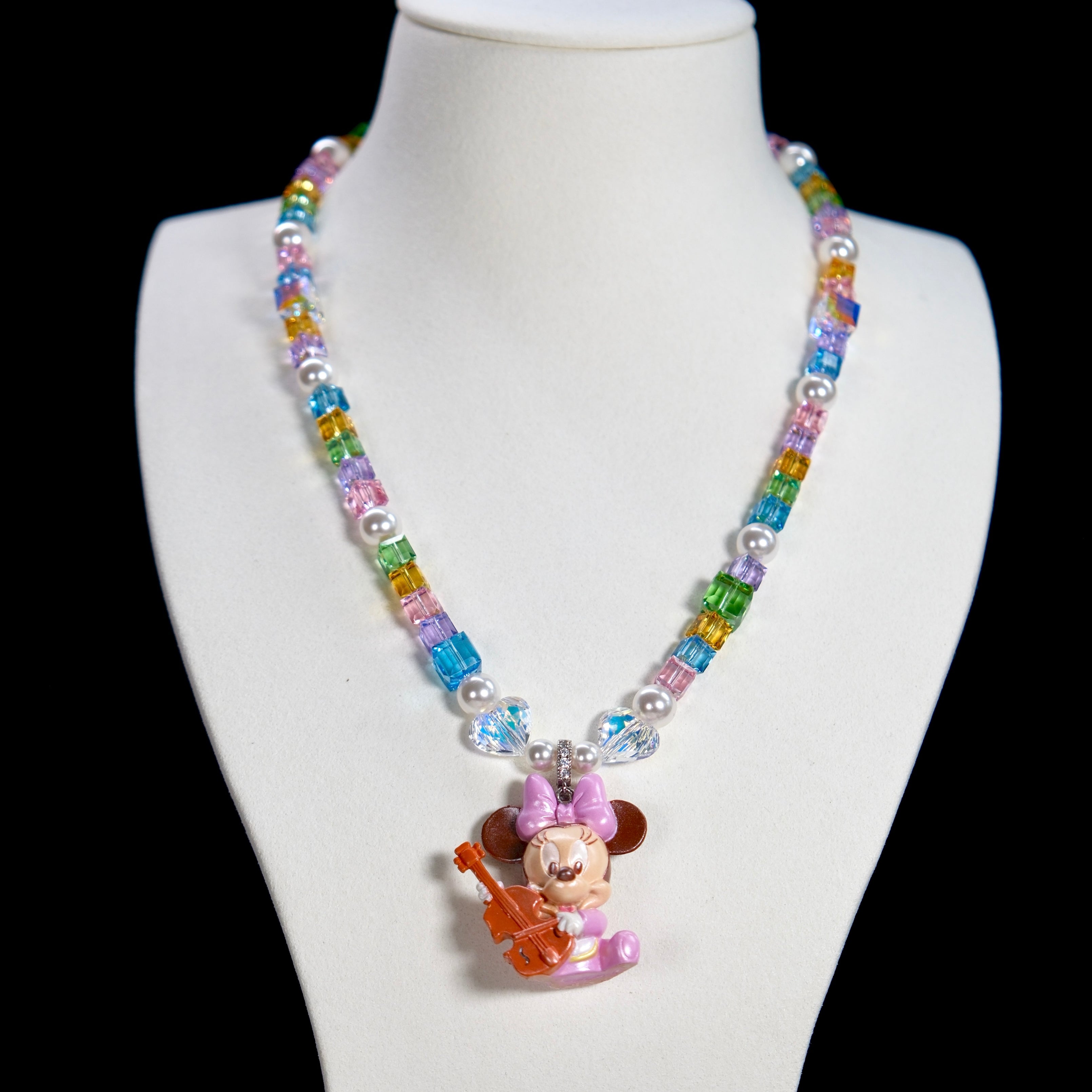 Close-up detail of a handmade rainbow Swarovski crystal charm necklace with pearls and vintage-inspired charm details.