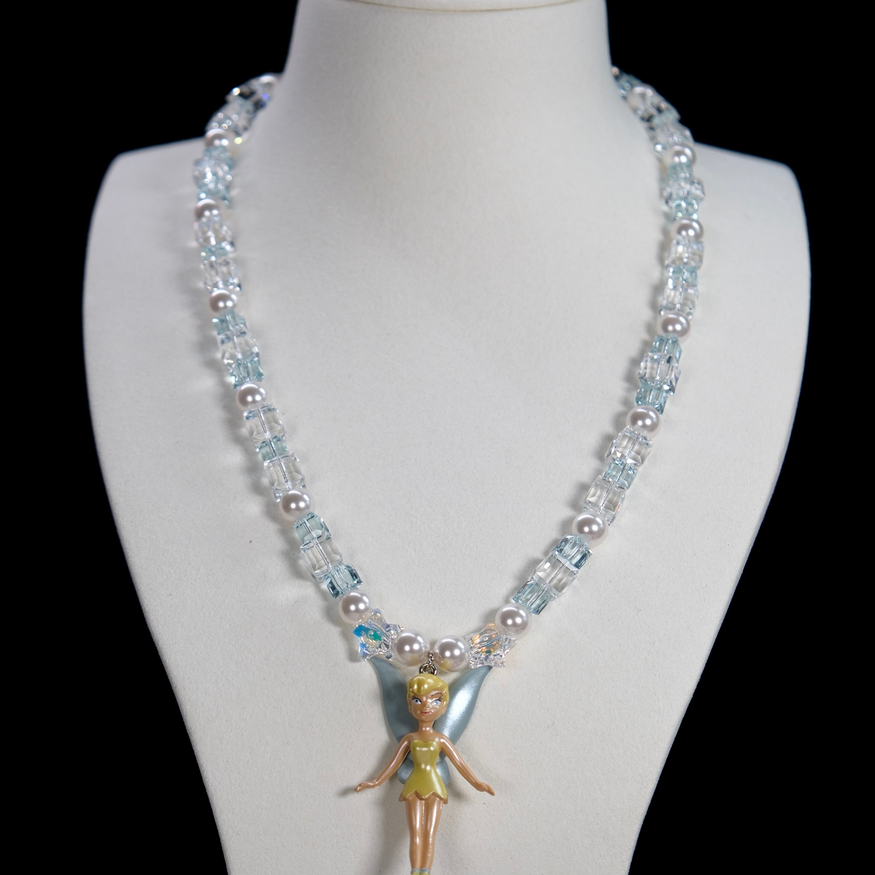 Close-up detail of a handmade blue Swarovski crystal charm necklace with pearls and vintage-inspired charm details.