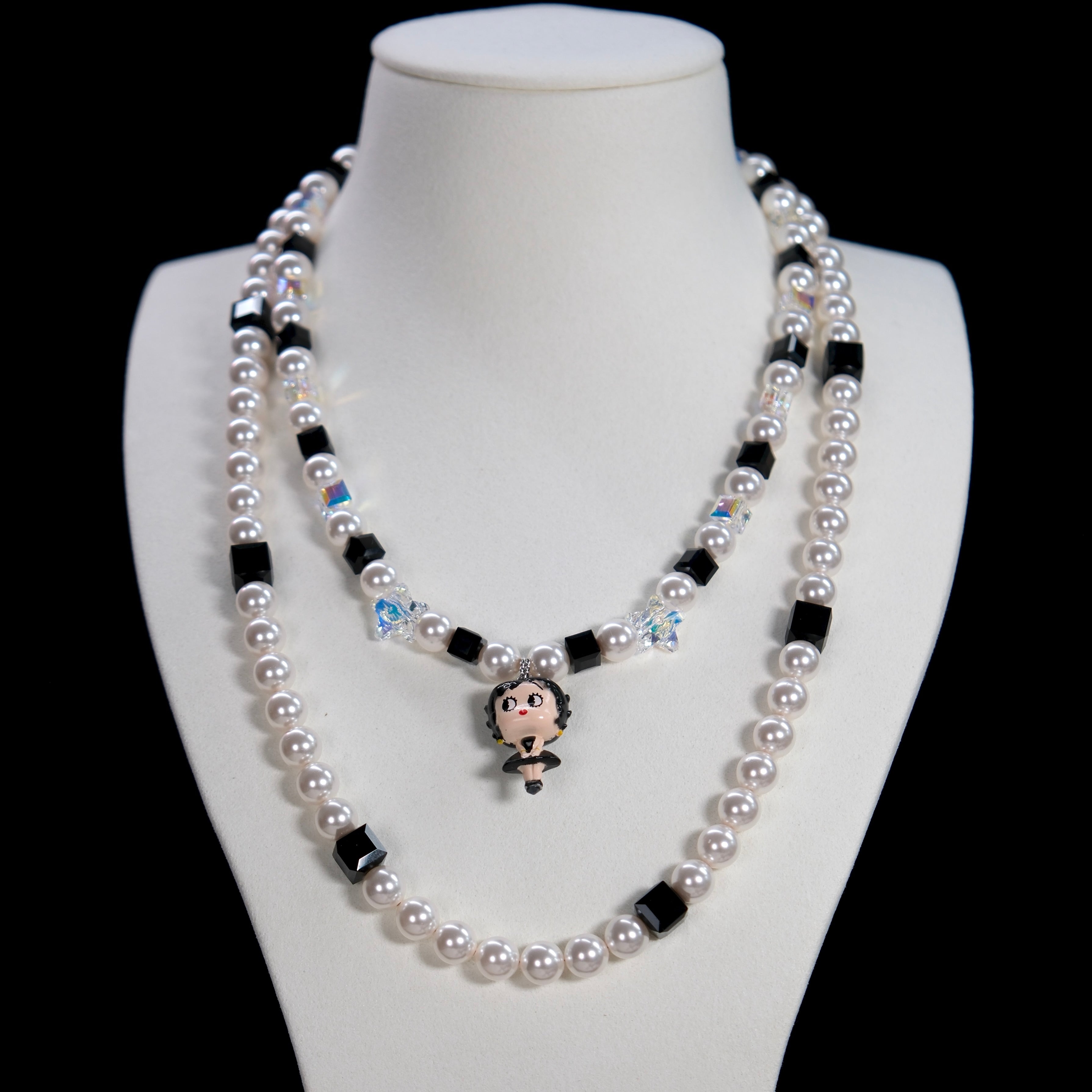 Close-up detail of a handmade black Swarovski crystal charm necklace with pearls and vintage-inspired charm details.