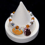Wrist view of a handmade cookie Swarovski crystal charm bracelet with pearls and playful charm details.