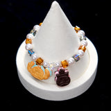 Wrist view of a handmade cookie Swarovski crystal charm bracelet with pearls and playful charm details.