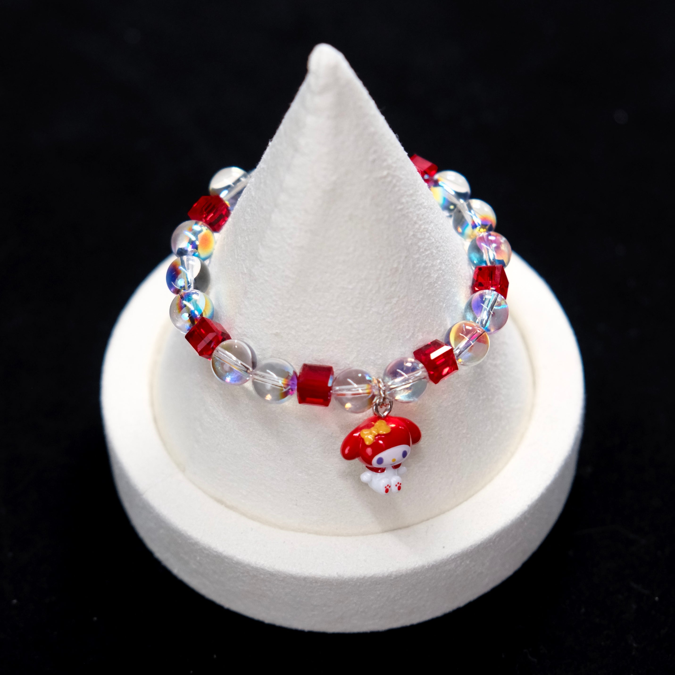 Wrist view of a handmade red Swarovski crystal charm bracelet with pearls and playful charm details.