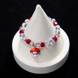 Wrist view of a handmade red Swarovski crystal charm bracelet with pearls and playful charm details.