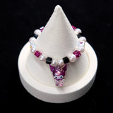 Wrist view of a handmade purple Swarovski crystal charm bracelet with pearls and playful charm details.