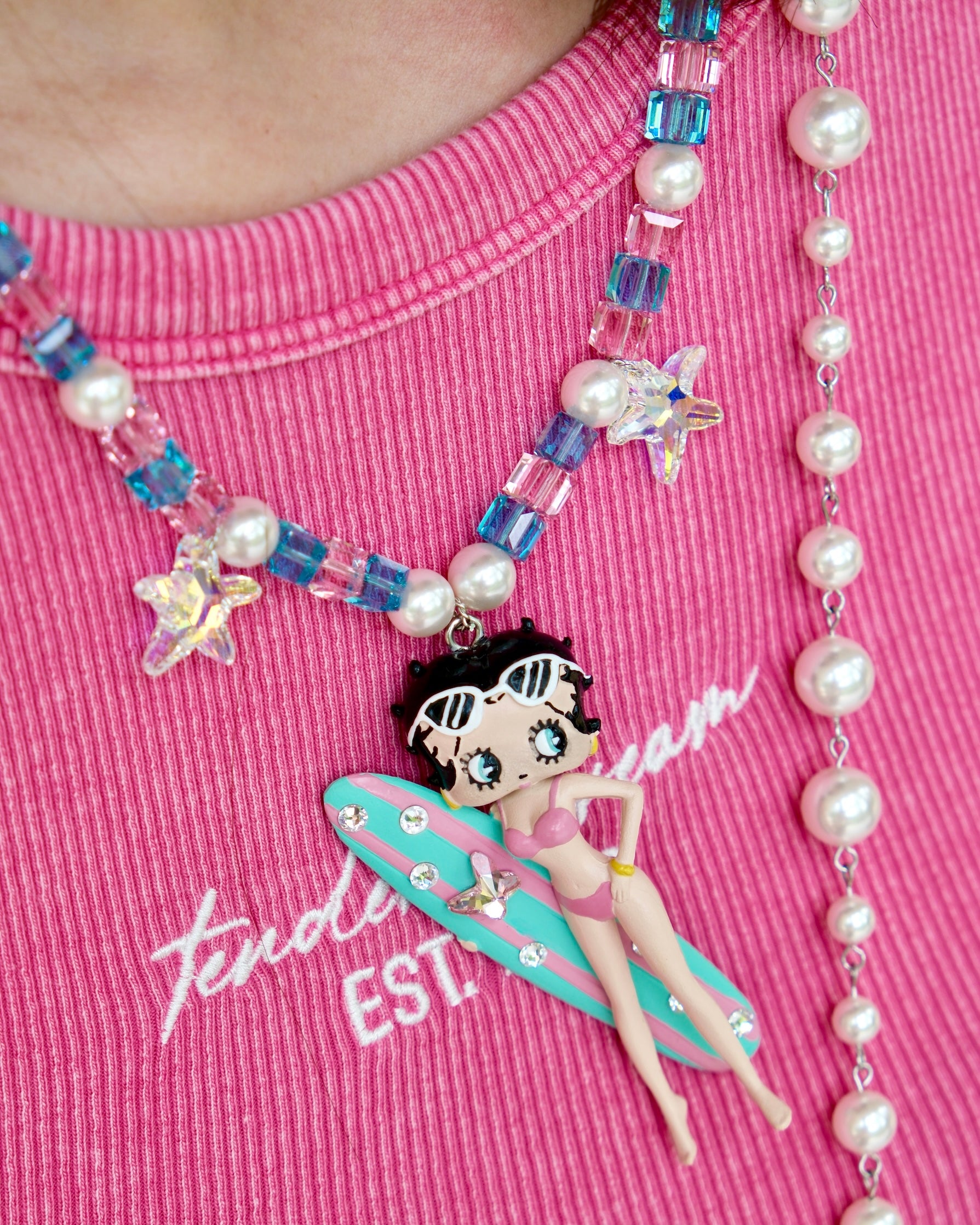 Close-up detail of a handmade pink Swarovski crystal charm necklace with pearls and vintage-inspired charm details.