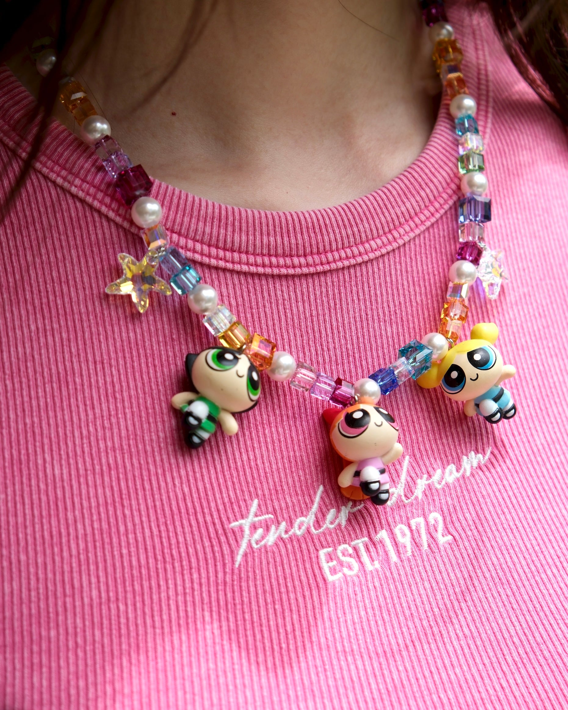 Close-up detail of a handmade colorful Swarovski crystal charm necklace with pearls and vintage-inspired charm details.
