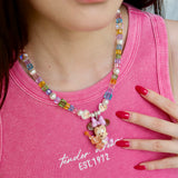 Close-up detail of a handmade rainbow Swarovski crystal charm necklace with pearls and vintage-inspired charm details.