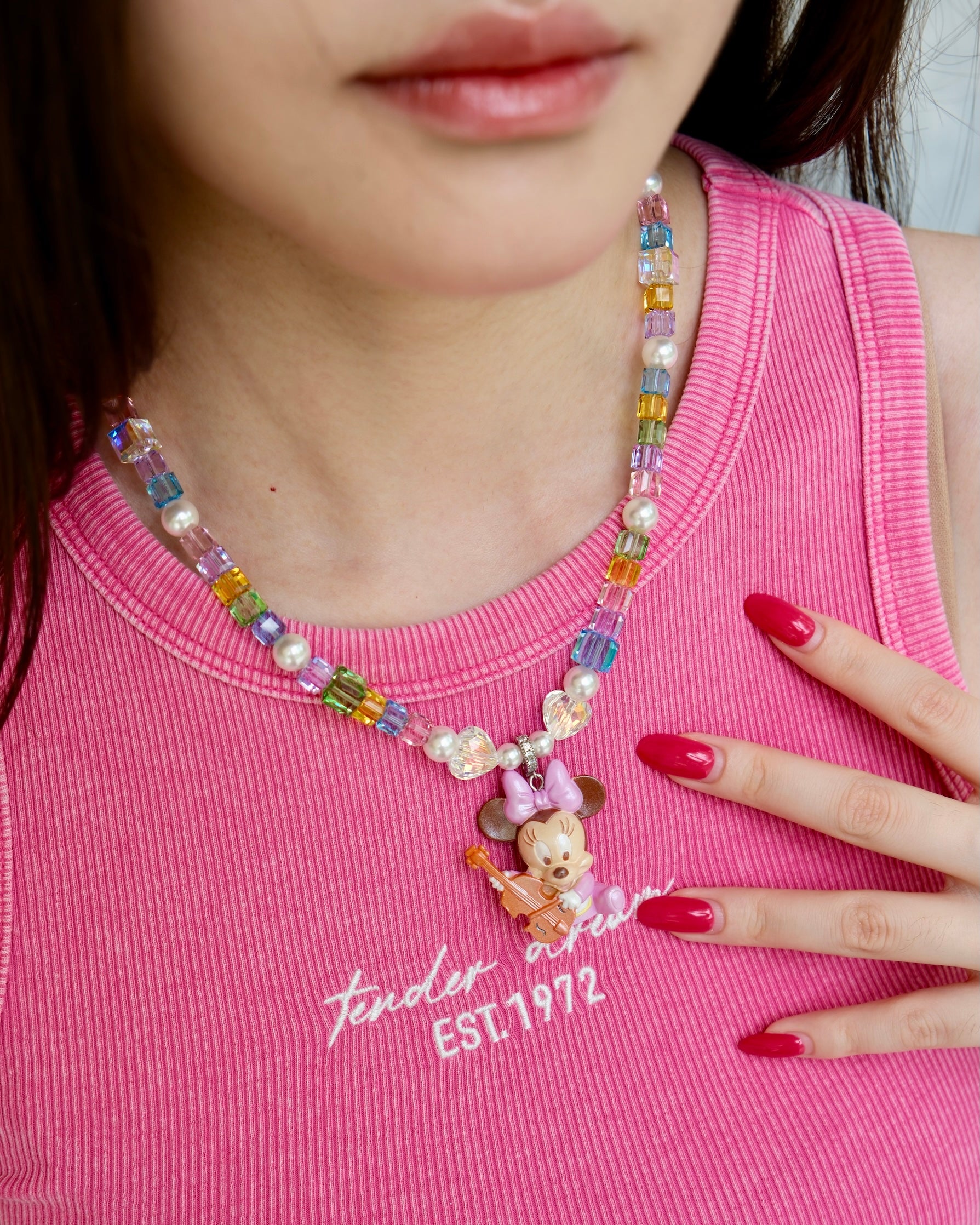 Close-up detail of a handmade rainbow Swarovski crystal charm necklace with pearls and vintage-inspired charm details.