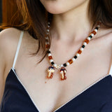 Close-up detail of a handmade colorful Swarovski crystal charm necklace with pearls and vintage-inspired charm details.