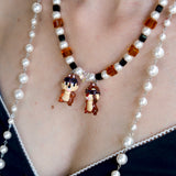 Close-up detail of a handmade colorful Swarovski crystal charm necklace with pearls and vintage-inspired charm details.
