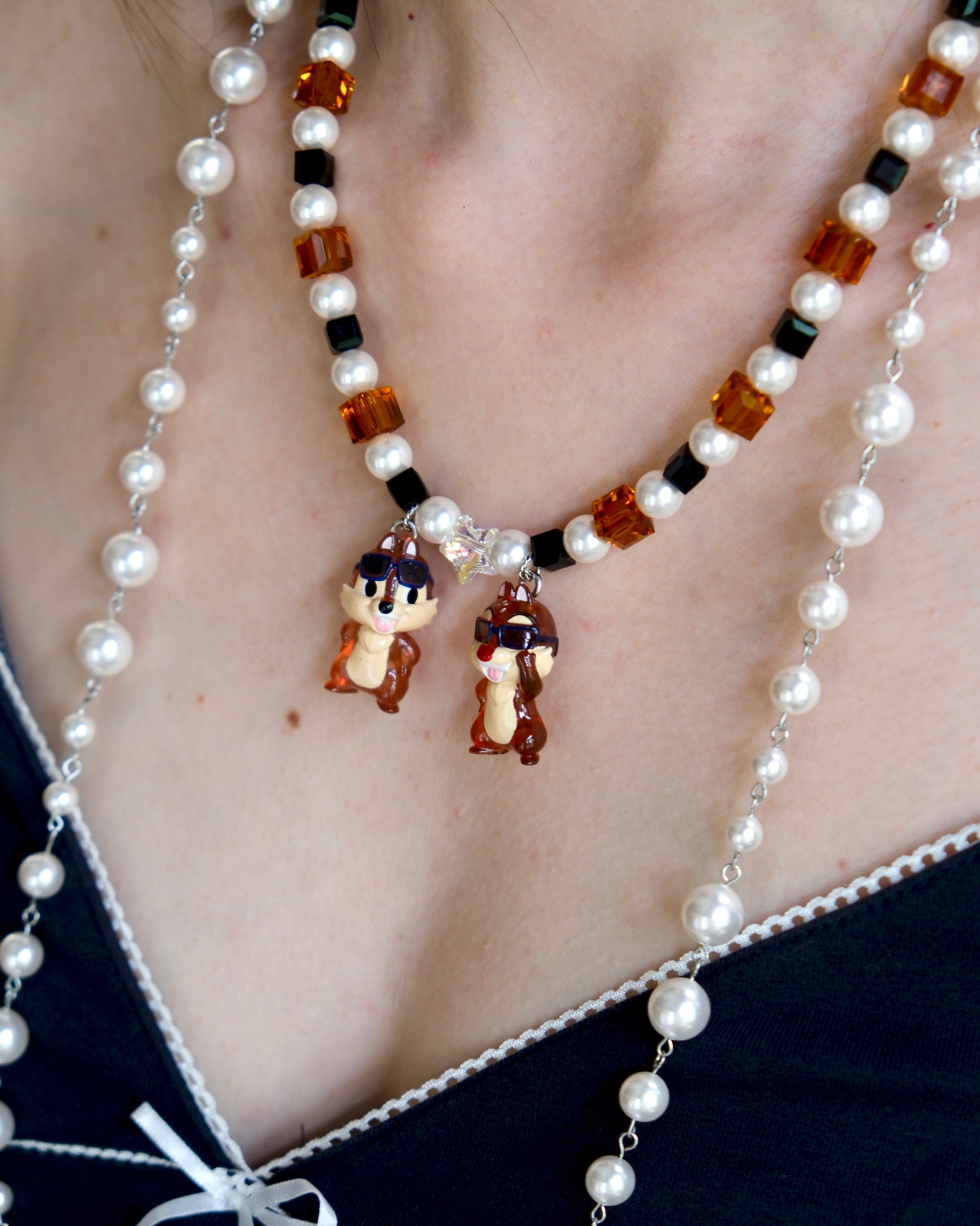 Close-up detail of a handmade colorful Swarovski crystal charm necklace with pearls and vintage-inspired charm details.