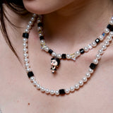 Close-up detail of a handmade black Swarovski crystal charm necklace with pearls and vintage-inspired charm details.