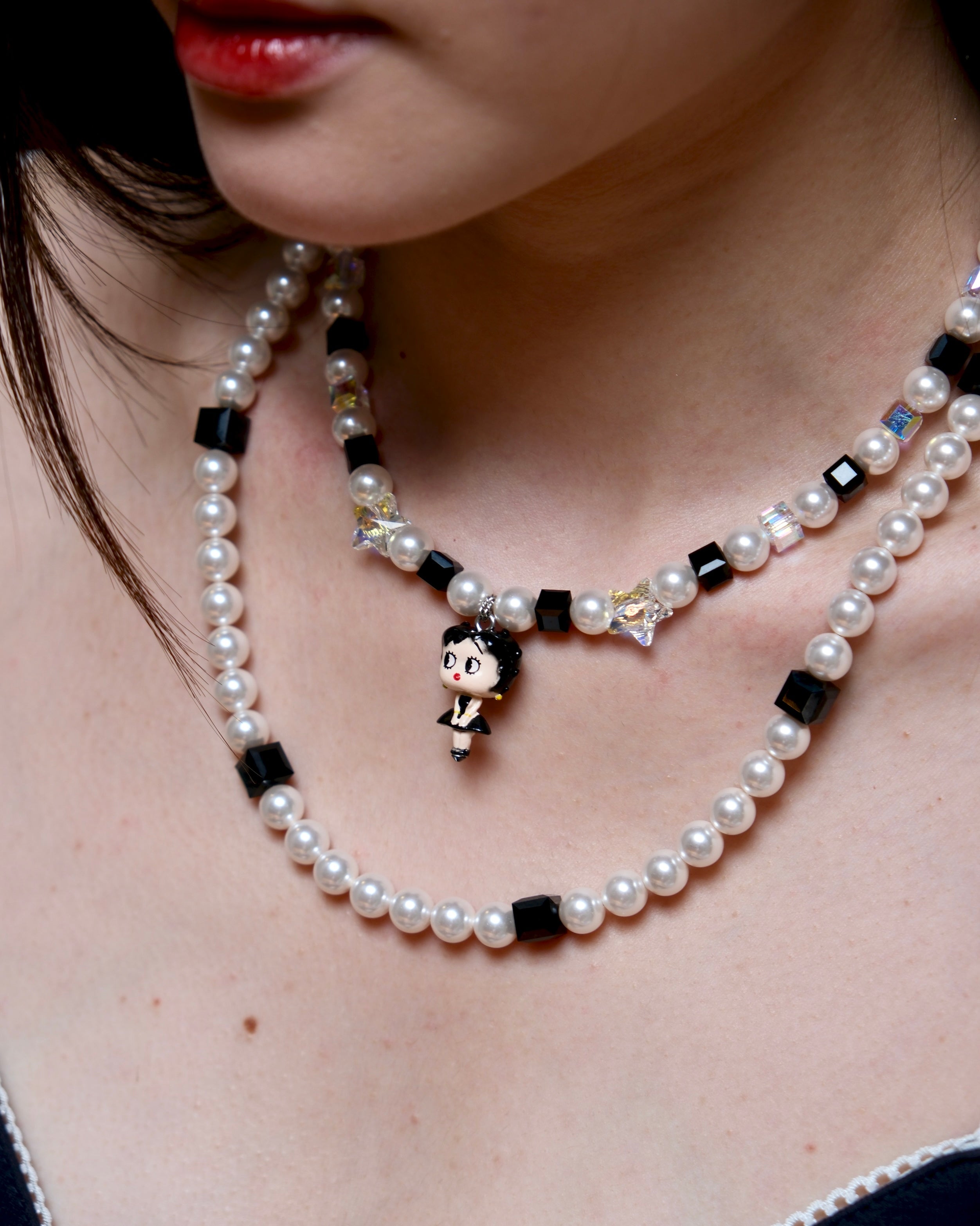 Close-up detail of a handmade black Swarovski crystal charm necklace with pearls and vintage-inspired charm details.