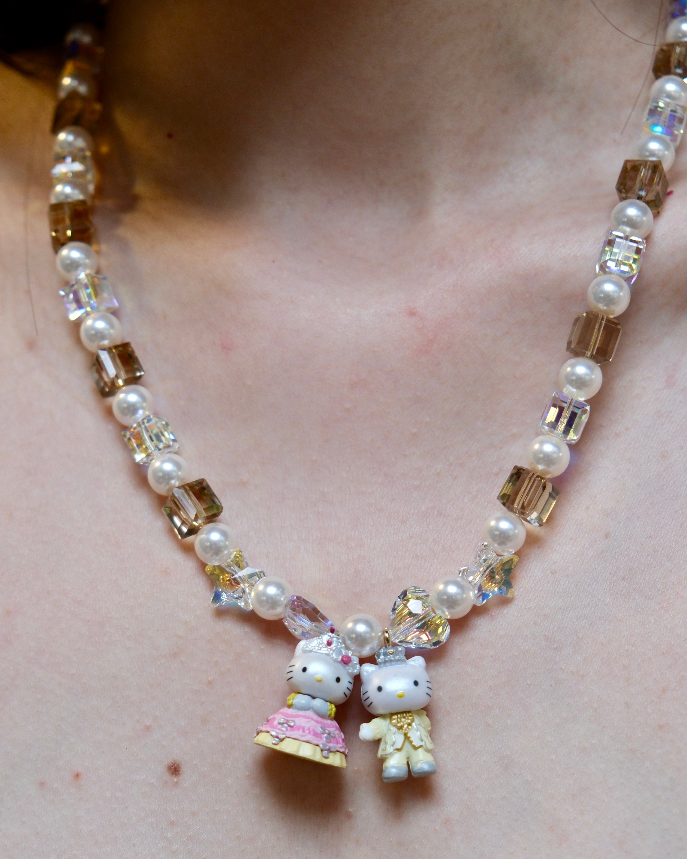 Close-up detail of a handmade colorful Swarovski crystal charm necklace with pearls and vintage-inspired charm details.