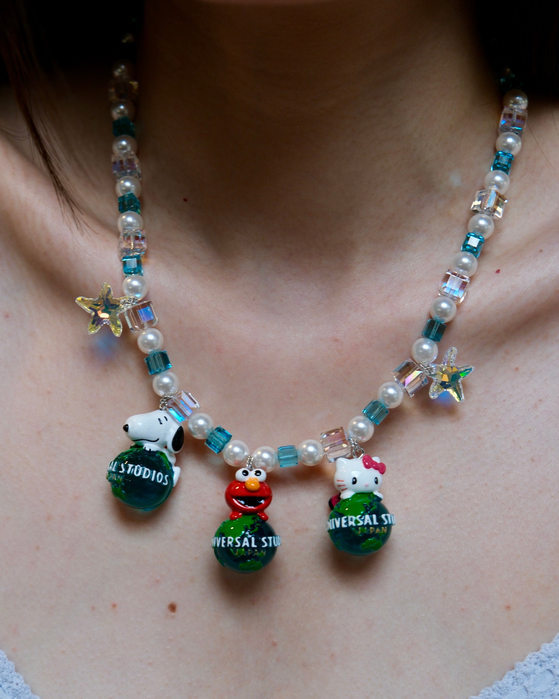 Close-up detail of a handmade colorful Swarovski crystal charm necklace with pearls and vintage-inspired charm details.