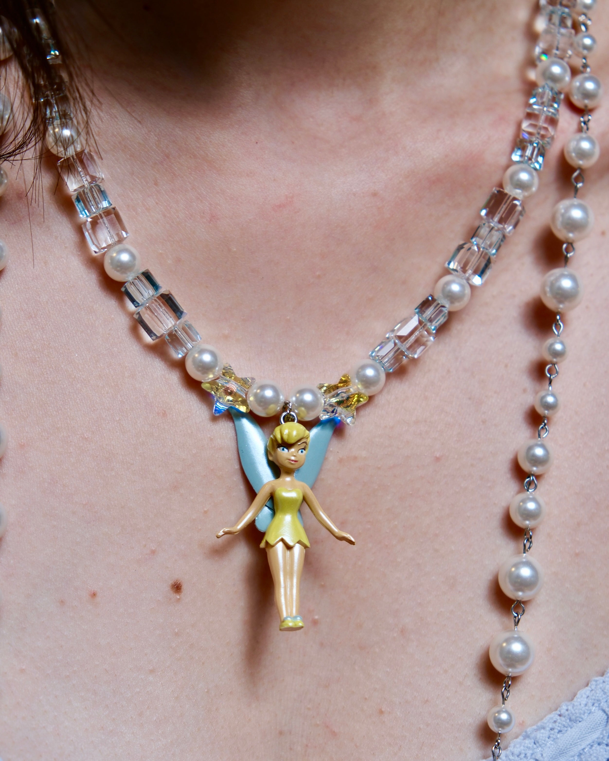 Close-up detail of a handmade blue Swarovski crystal charm necklace with pearls and vintage-inspired charm details.