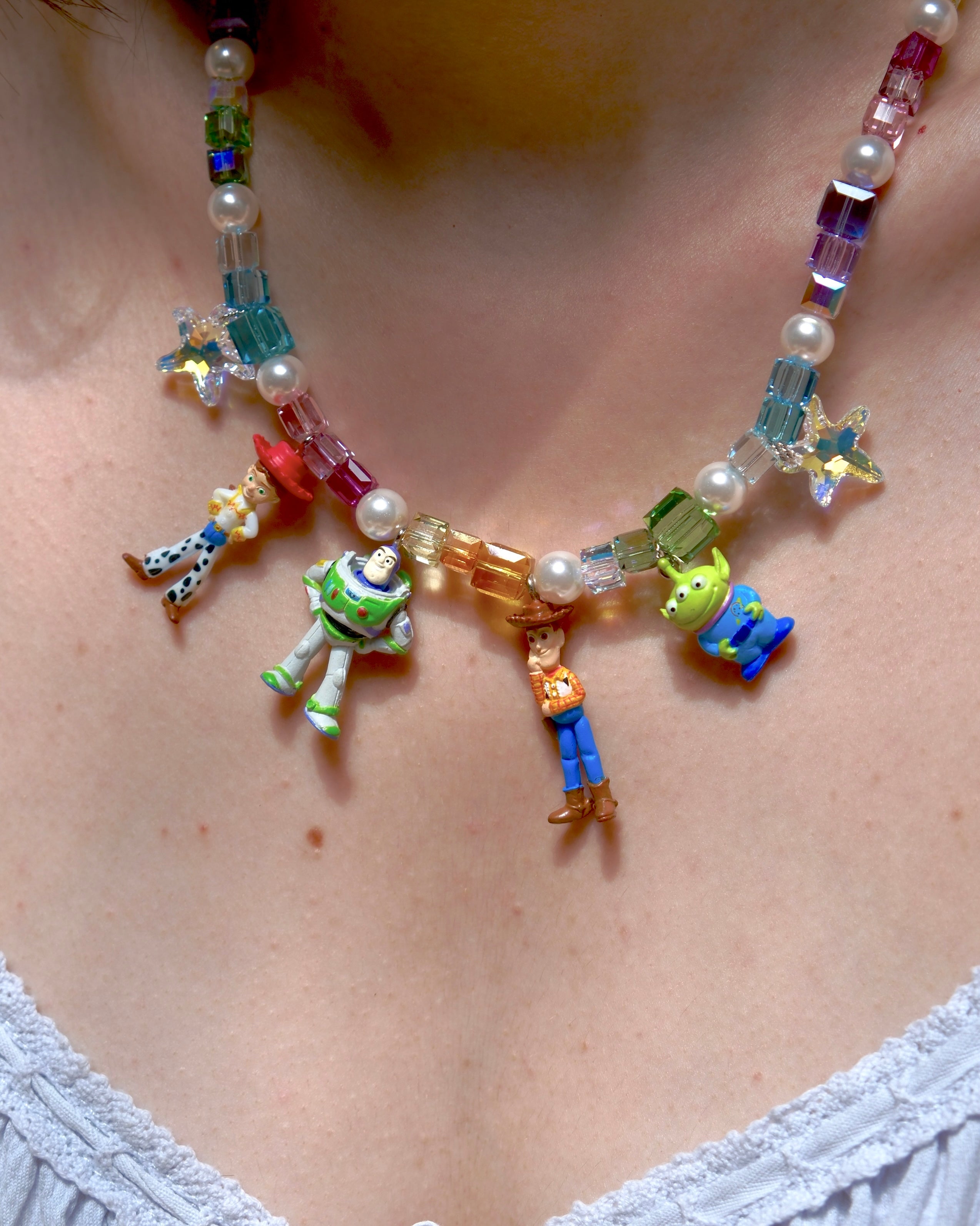 Close-up detail of a handmade rainbow Swarovski crystal charm necklace with pearls and vintage-inspired charm details.