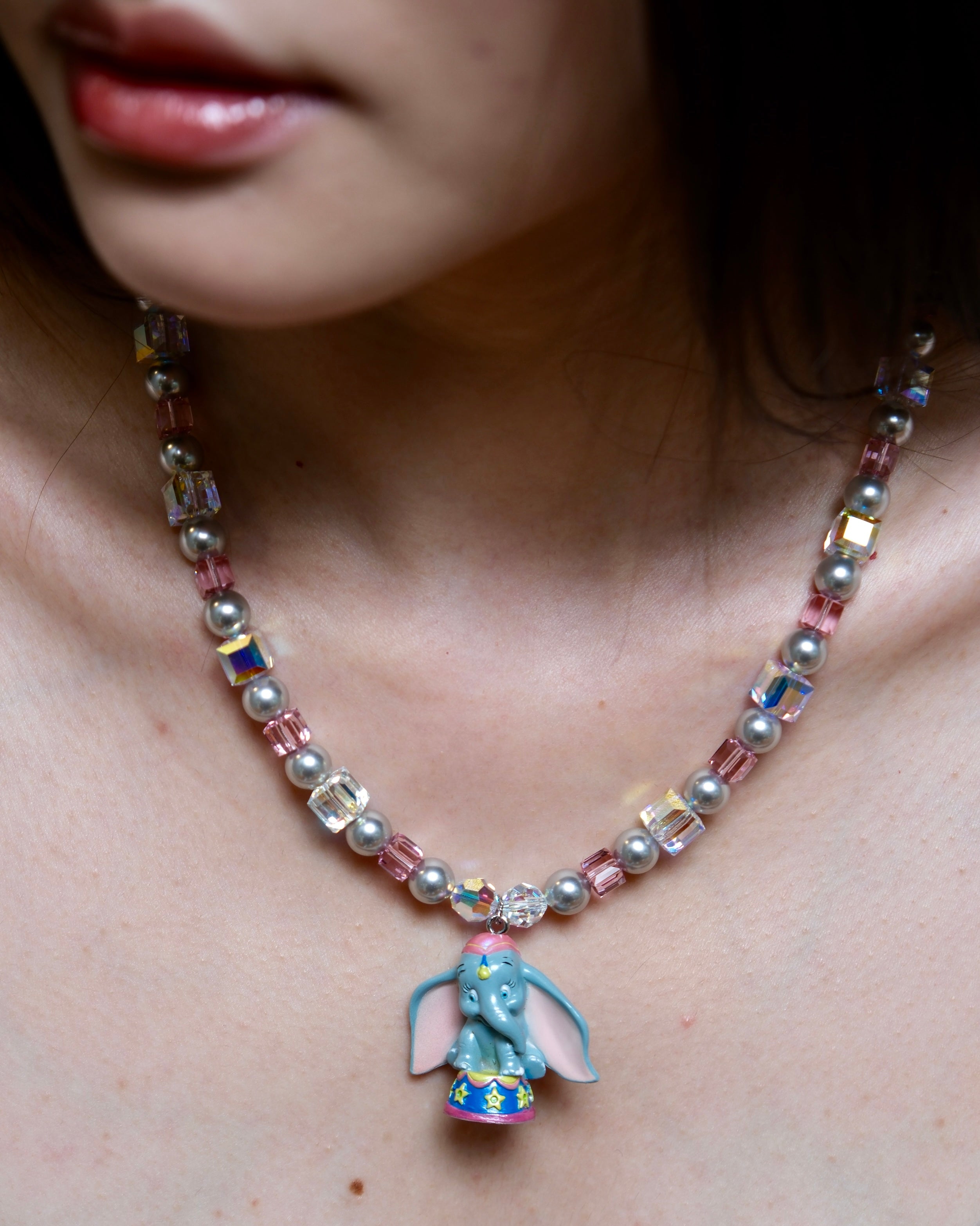 Detailed view of a handmade blue elephant charm necklace with gray Swarovski pearls, pink beads, and iridescent crystal accents.