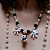 Model wearing a handmade colorful Swarovski crystal charm necklace with pearls and three playful collectible charms.