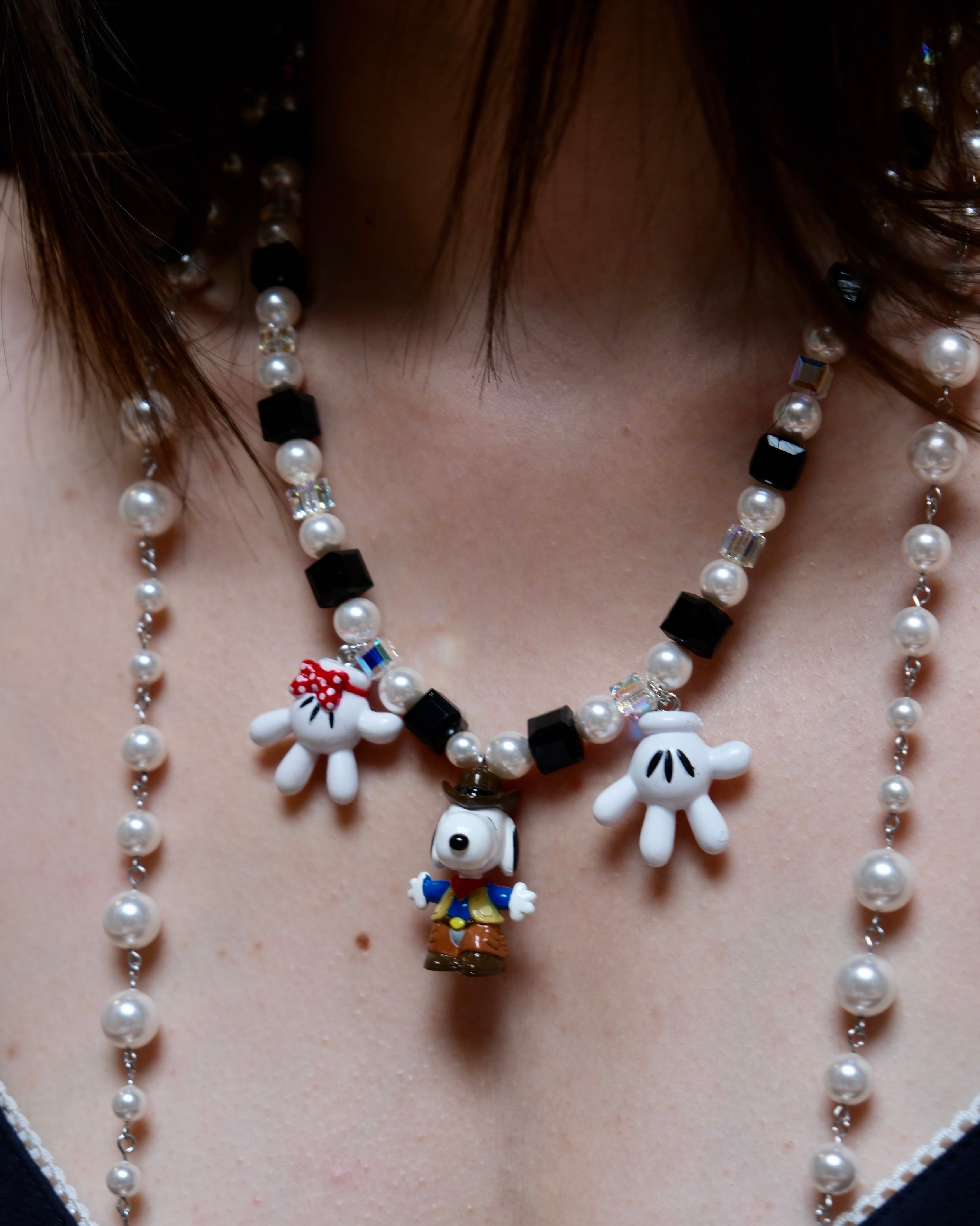 Model wearing a handmade colorful Swarovski crystal charm necklace with pearls and three playful collectible charms.