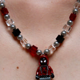 Model wearing a handmade red, black, and clear crystal charm necklace with pearl accents and a city-inspired collectible pendant.