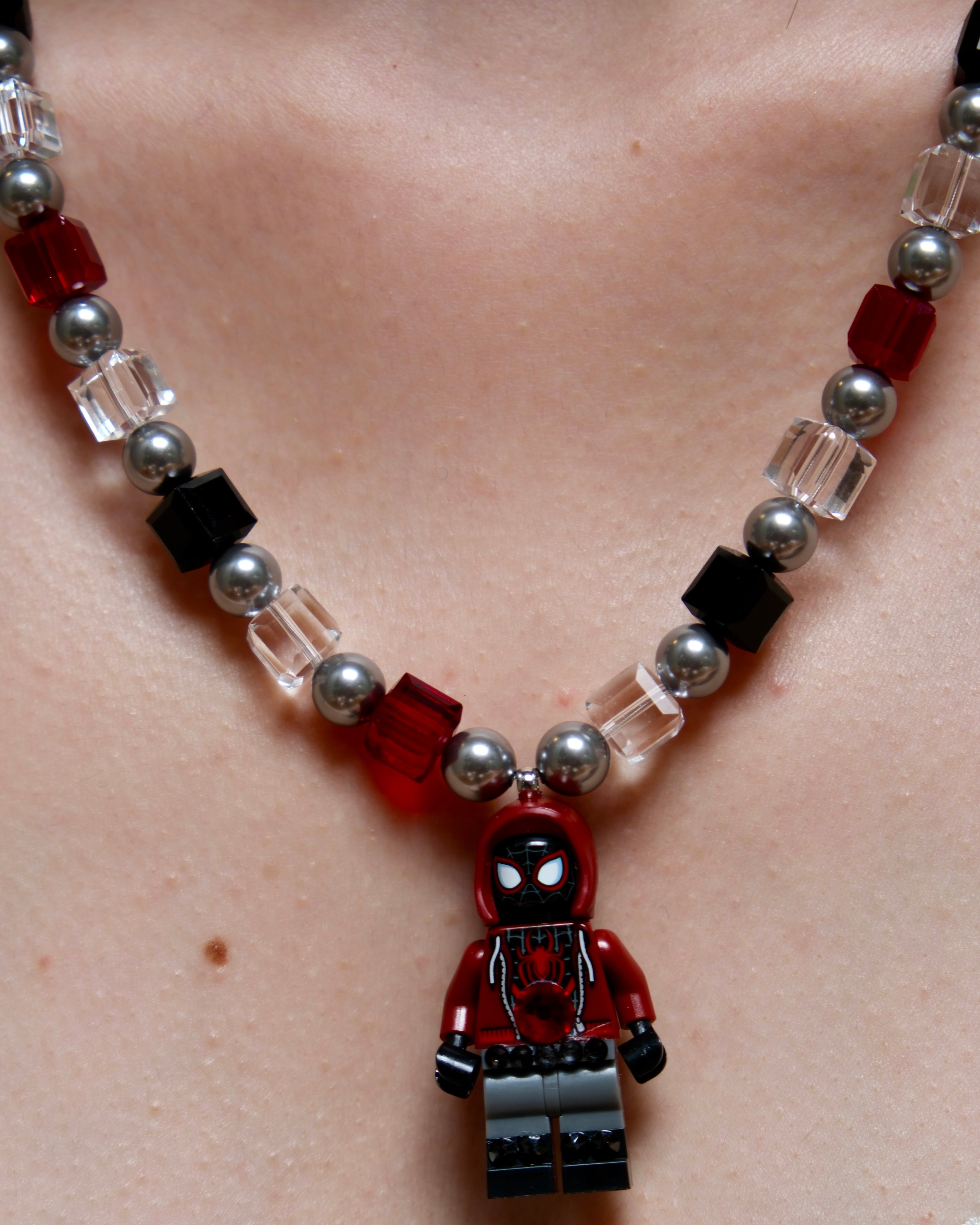 Model wearing a handmade red, black, and clear crystal charm necklace with pearl accents and a city-inspired collectible pendant.