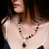 Model wearing a handmade pastel crystal charm necklace with white pearl accents and a playful vintage-inspired pendant.